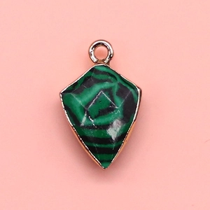 Macro detail of shield-shaped malachite stone pendant with golden metal frame and top ring