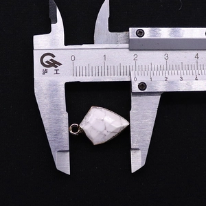 Detail of white turquoise arrow pendant with gold plated edges and measurement gauge