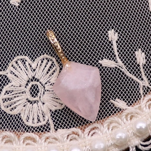 Macro de pendentif en quartz rose facetté avec bélière dorée sur tissu dentelle