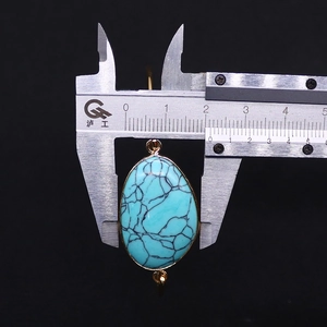 Detail showing an 18mm turquoise stone pendant with golden trim and measurement scale