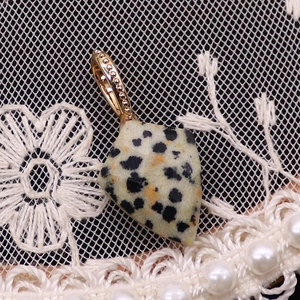 Vue macro du pendentif Jaspe Dalmatien en forme de cerf-volant avec fermoir doré sur dentelle