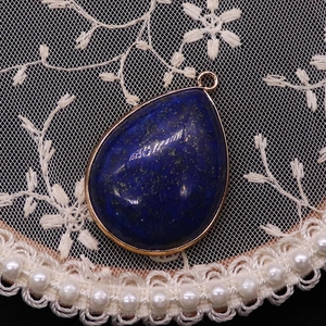 Detailed view of teardrop lapis lazuli pendant with gold plating and blue stone texture