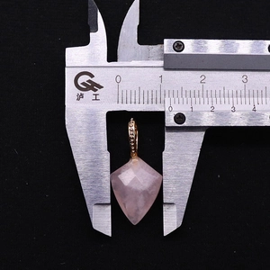 Vue macro d'un pendentif en cristal rose facetté mesuré avec un pied à coulisse