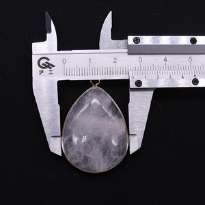 Detail view of water drop crystal pendant being measured with a caliper showing width