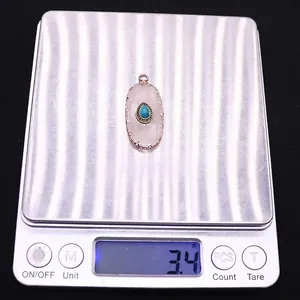 Macro shot of oval quartz pendant weighing 3.4g on digital scale with turquoise detail
