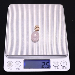 Macro d'un pendentif en cristal rose pesé sur une balance numérique de précision