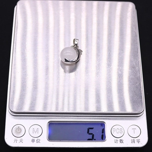 Macro view of a 5.1g natural stone dolphin pendant on a digital scale for weight detail