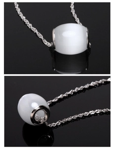 Macro detail of white opal bead pendant on a silver twisted chain with reflections