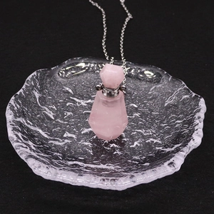 Vue détaillée d'un pendentif flacon d'huile essentielle en quartz rose avec bouchon argenté