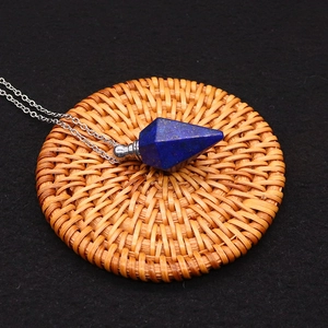 Detailed view of a lapis lazuli hexagonal crystal perfume bottle pendant on a woven mat