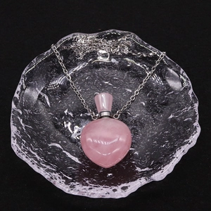 Detail der herzförmigen rosa Kristall-Parfümflaschen-Halskette mit Silberkette auf Glastablett
