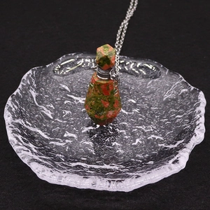 Gros plan d'un pendentif flacon de parfum en unakite facettée sur une chaîne en métal