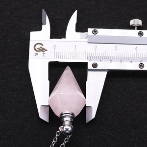 Macro scatto che mostra la misura di 1,9 cm del ciondolo a boccetta di quarzo rosa esagonale