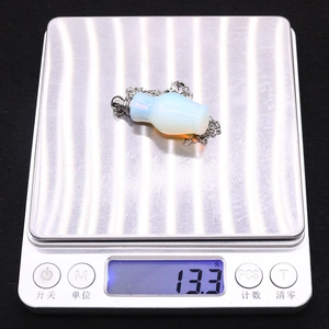 Detail showing an opal perfume bottle necklace on a digital scale weighing 13.3 grams