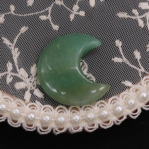 Polished green natural stone moon-shaped bead on white lace with pearl detail decoration
