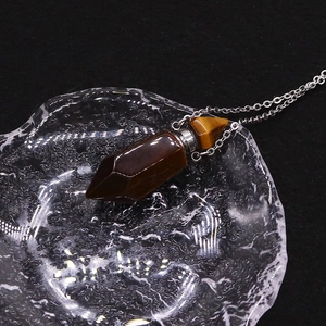 Macro view of a hexagonal tiger eye stone perfume bottle pendant with silver chain