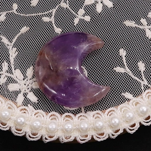 Macro shot of polished moon-shaped amethyst stone with natural purple textures on lace