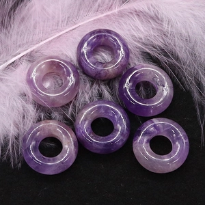 Macro di sei perle donut in ametista viola naturale con venature su sfondo nero elegante