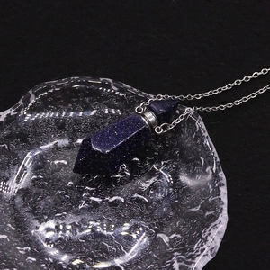 Macro shot of blue sandstone hexagonal perfume bottle necklace on water ripple tray