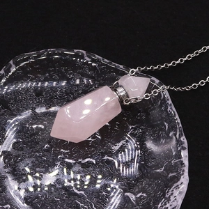 Macro shot of rose quartz hexagonal prism perfume bottle pendant with silver chain