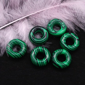Vista macro di sei perline di malachite verde a forma di ciambella per gioielli fai da te
