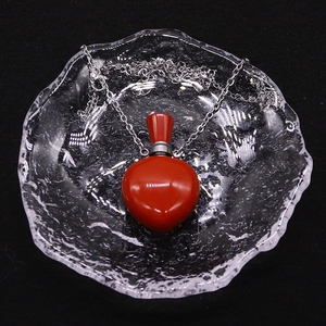 Rote herzförmige ätherische Ölflasche Halskette auf einem gewellten Glastablett