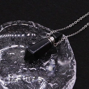 Macro shot of a black obsidian hexagonal prism perfume bottle pendant with silver chain