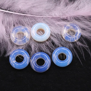 Vista macro di perle donut in opalite blu e piuma viola su velluto nero elegante