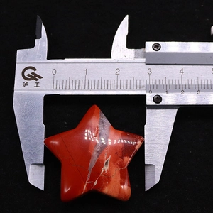 Measuring star-shaped red jasper stone with caliper showing 31mm width detail