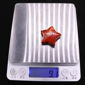 Star-shaped red jasper gemstone shown weighing 9.1 grams on a digital scale
