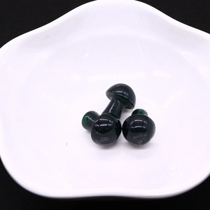 Detailed macro view of three green mushroom stones with drilled holes on a white plate