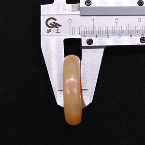 Macro shot measuring the 8-9mm width of the natural yellow agate ring with a digital caliper