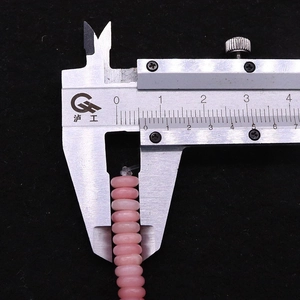 Macro dettagliata di perle rosa da 8,5 mm misurate con un calibro a corsoio in metallo