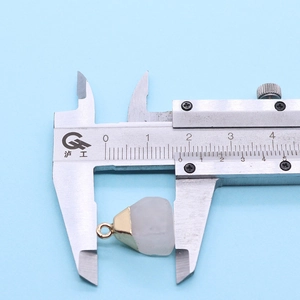 Detailed measurement of semi-precious stone pendant with gold trim using a caliper