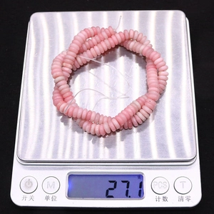 Perle tonde piatte in pietra naturale rosa pesate su una bilancia digitale 27,1g