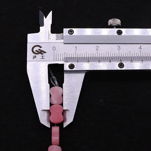 Macro-opname van een 10mm roze vlinderkraal gemeten met een digitale schuifmaat