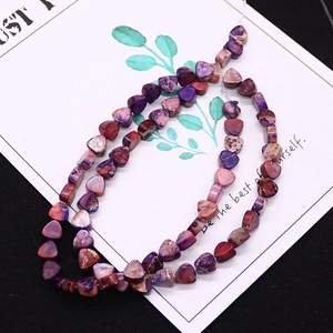 Detailed close-up of heart-shaped emperor stone beads in purple and magenta for DIY jewelry