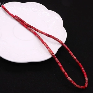 Macro detail of red stone tube beads with natural texture on a white decorative plate