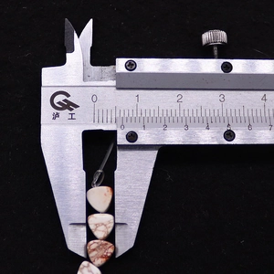 Measuring 10mm triangle turquoise stone beads with a metal digital caliper tool