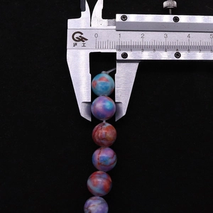 Detailed view of 10mm colorful dyed marble-textured stone beads with a digital caliper measurement