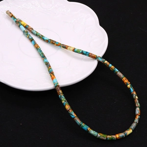 Close-up of 4x8mm colorful natural stone cylinder beads scattered on a textured dish