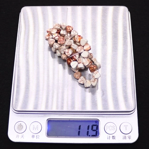 Flat triangle natural emperor stone beads on electronic scale showing 11.9g weight