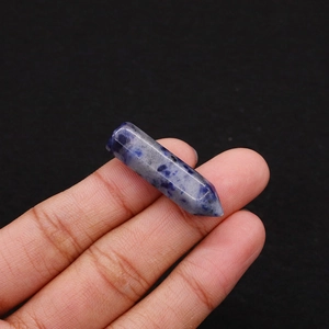 Macro detail of a polished hexagonal sodalite crystal pillar held between fingers