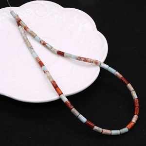Detailed macro view of 4x8mm imperial stone beads on a decorative white ceramic plate