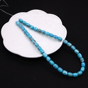 Close-up of 8x10mm blue turquoise drum beads for jewelry making on a white petal plate