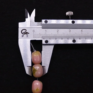 Close-up measurement of 10mm pink emperor stone cylinder bead with digital caliper tool