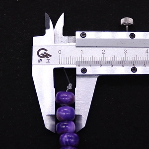 Detailaufnahme von 14,5 mm lila Kaiserstein-Perlen, gemessen mit einem Messschieber