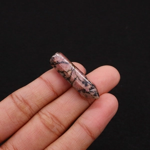 Macro shot of a pink rhodonite hexagonal crystal point with natural black veins