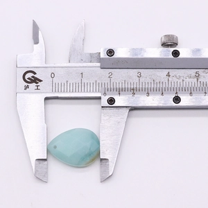 Detailed macro view showing teardrop gemstone width being measured with a caliper