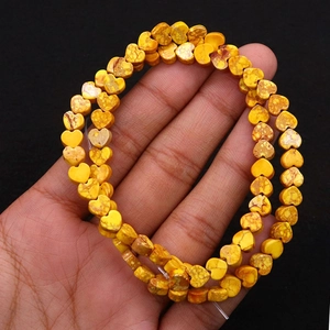 Macro detail of heart-shaped natural yellow stone beads with dark brown textures for DIY